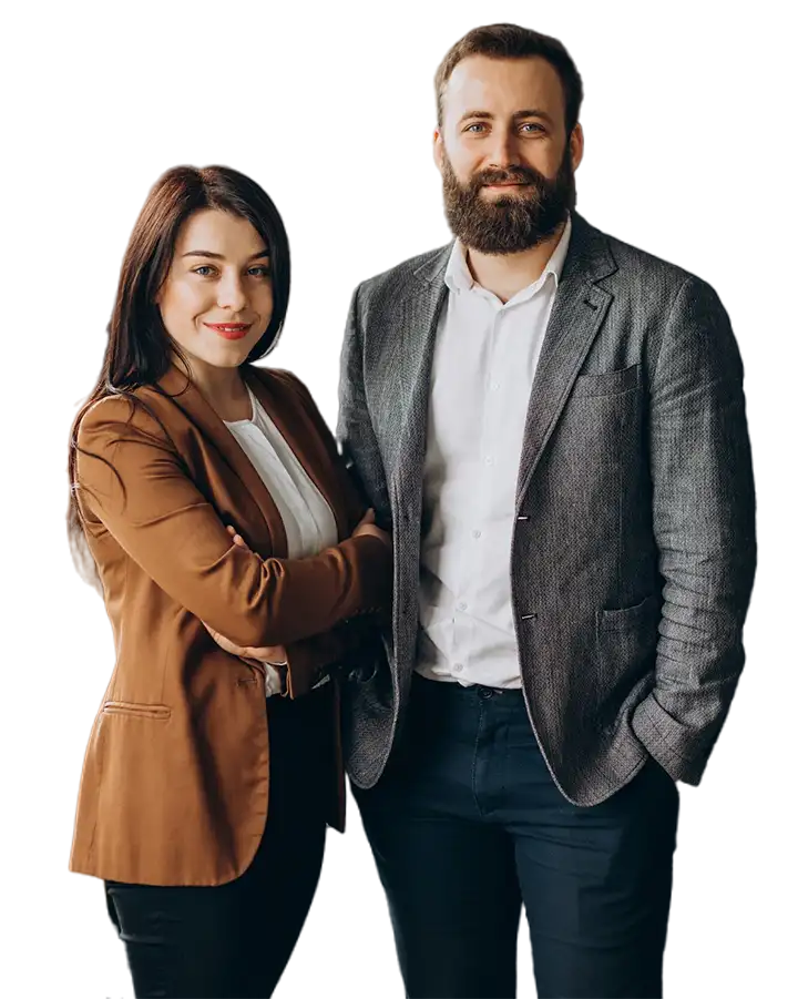 Professional man and woman standing side by side in business attire, smiling confidently with arms relaxed and crossed.