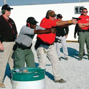 Law enforcement officers participating in live-fire handgun training at an outdoor shooting range.
