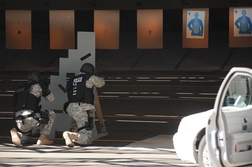 Two people in a scuffle in a graffiti-covered hallway, with another person watching nearby.
