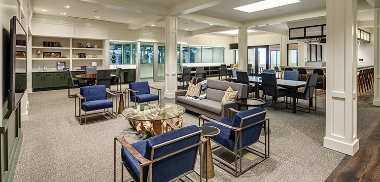 Chairs and table sit in a modern lounge with shelves and large windows, creating a cozy atmosphere.