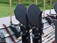 Steel popper targets mounted on a horizontal rail system at an outdoor shooting range.