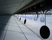 Indoor shooting range with hanging round steel targets and paper silhouette targets.