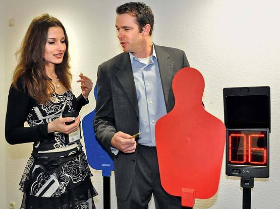 Two people stand by colored silhouettes and a digital timer showing "06" in a room.