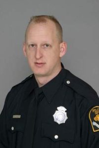 Portrait of a uniformed law enforcement officer against a neutral background.