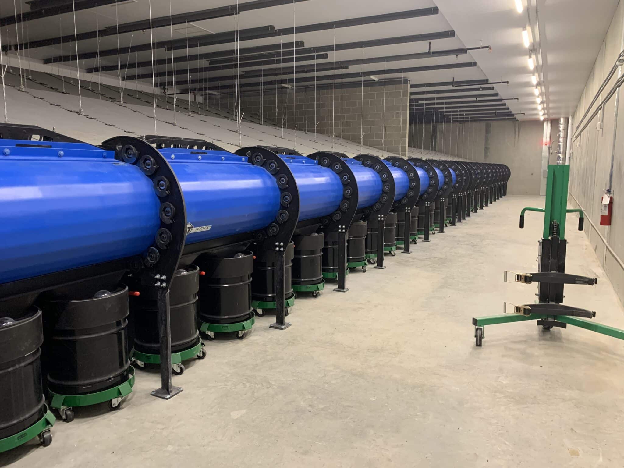 Indoor shooting range bullet trap and ventilation system with cylindrical steel collection units.