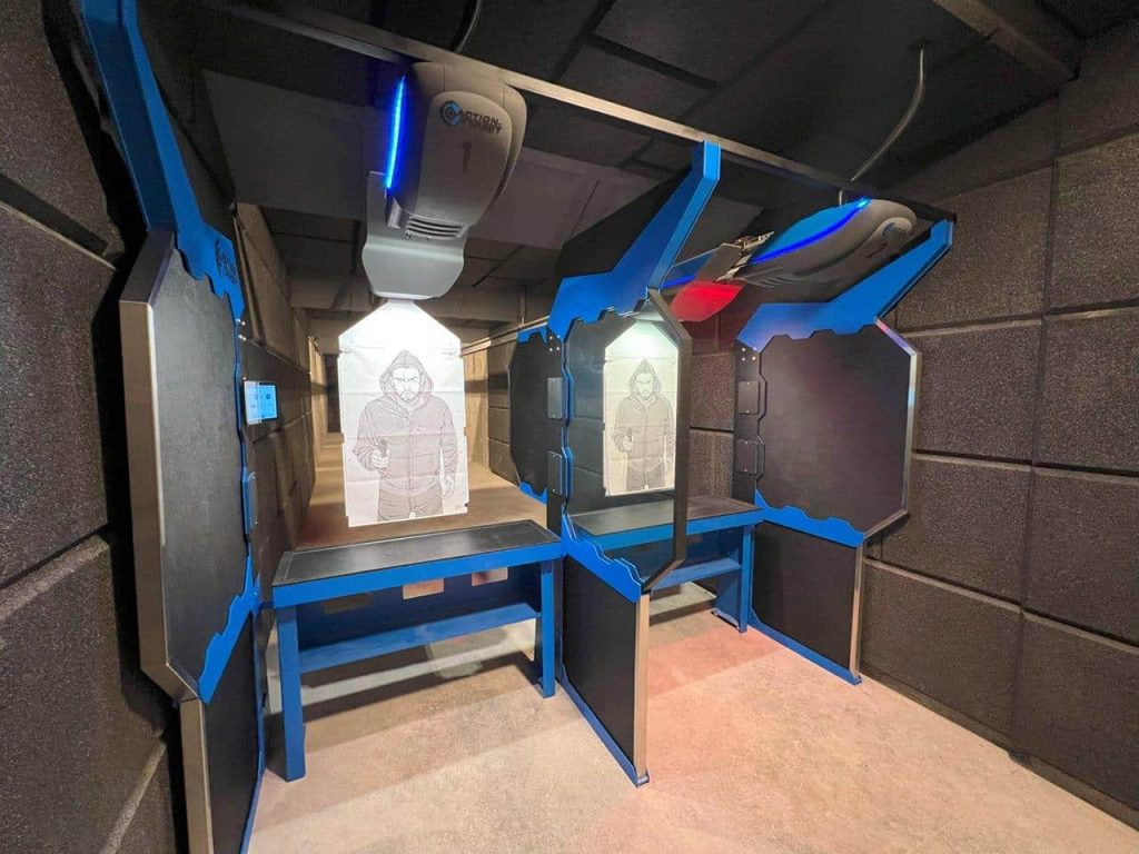 Indoor shooting range lanes with target retrievers and silhouette paper targets displayed at each station.