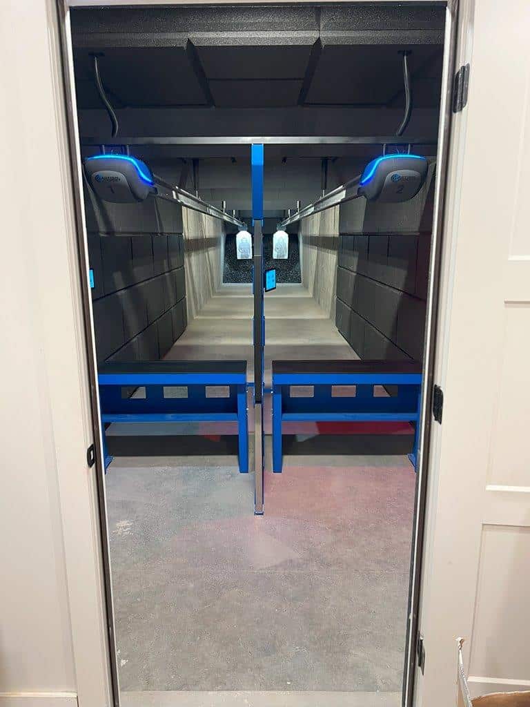 Indoor shooting range lanes with blue shooting stalls and target retrieval system.