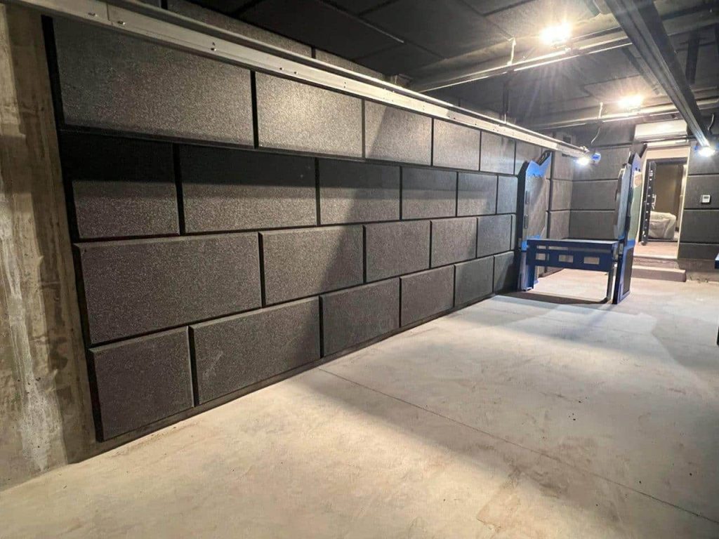 Dark gray padded room with a blue safety gate; dimly lit, industrial setting.