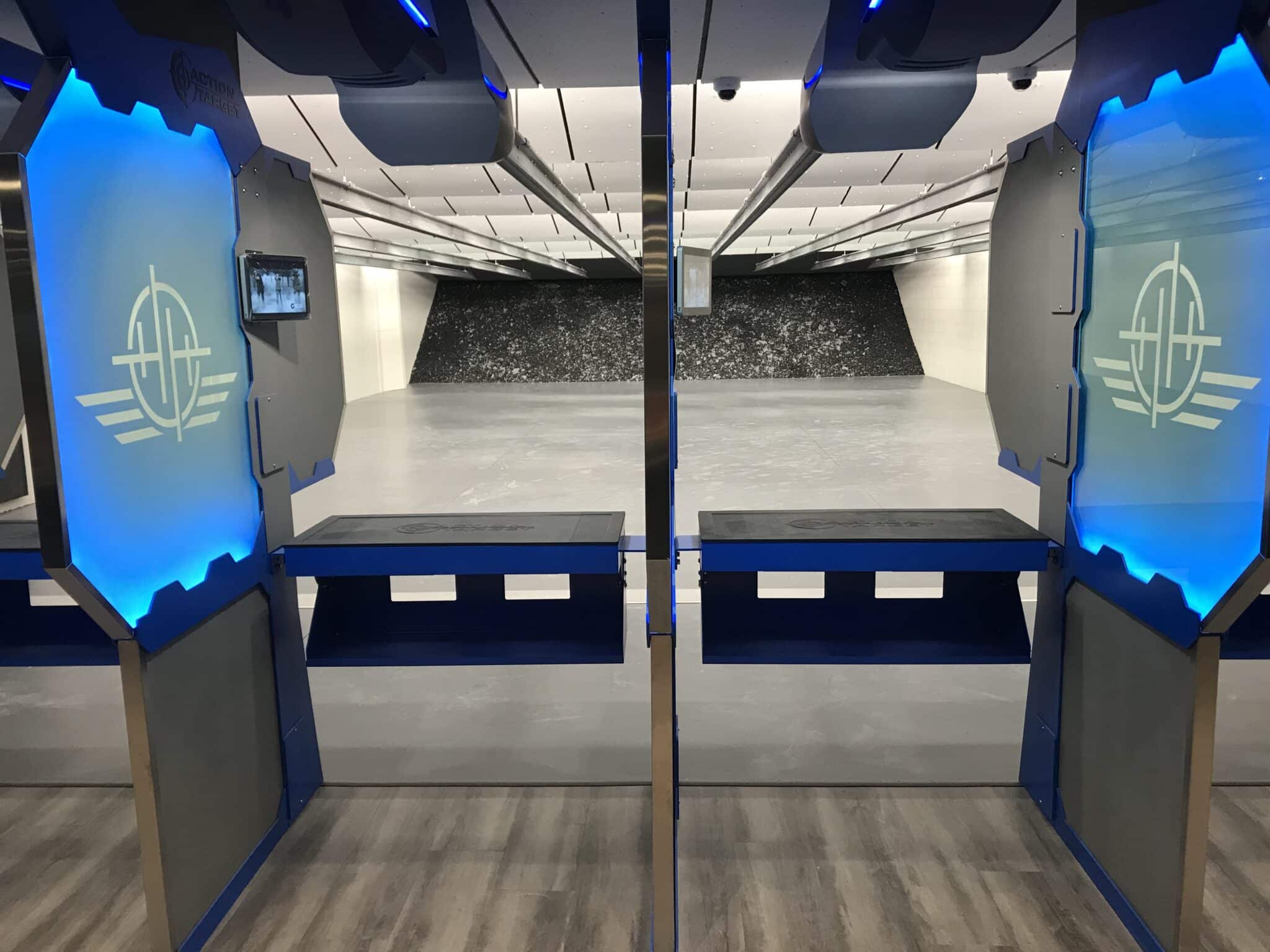 Two shooting lanes with blue dividers in an indoor shooting range; targets distance away.