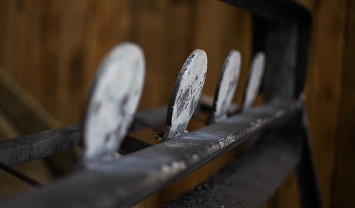 Close-up of worn steel shooting targets on a rack inside an indoor range facility.