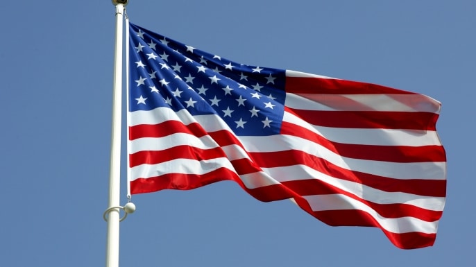 An photo of an American flag flying at full mast wrinkled slightly as it waves in the breeze.