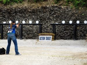 Shooter aiming at steel plate targets during an outdoor shooting competition with Action Target equipment.
