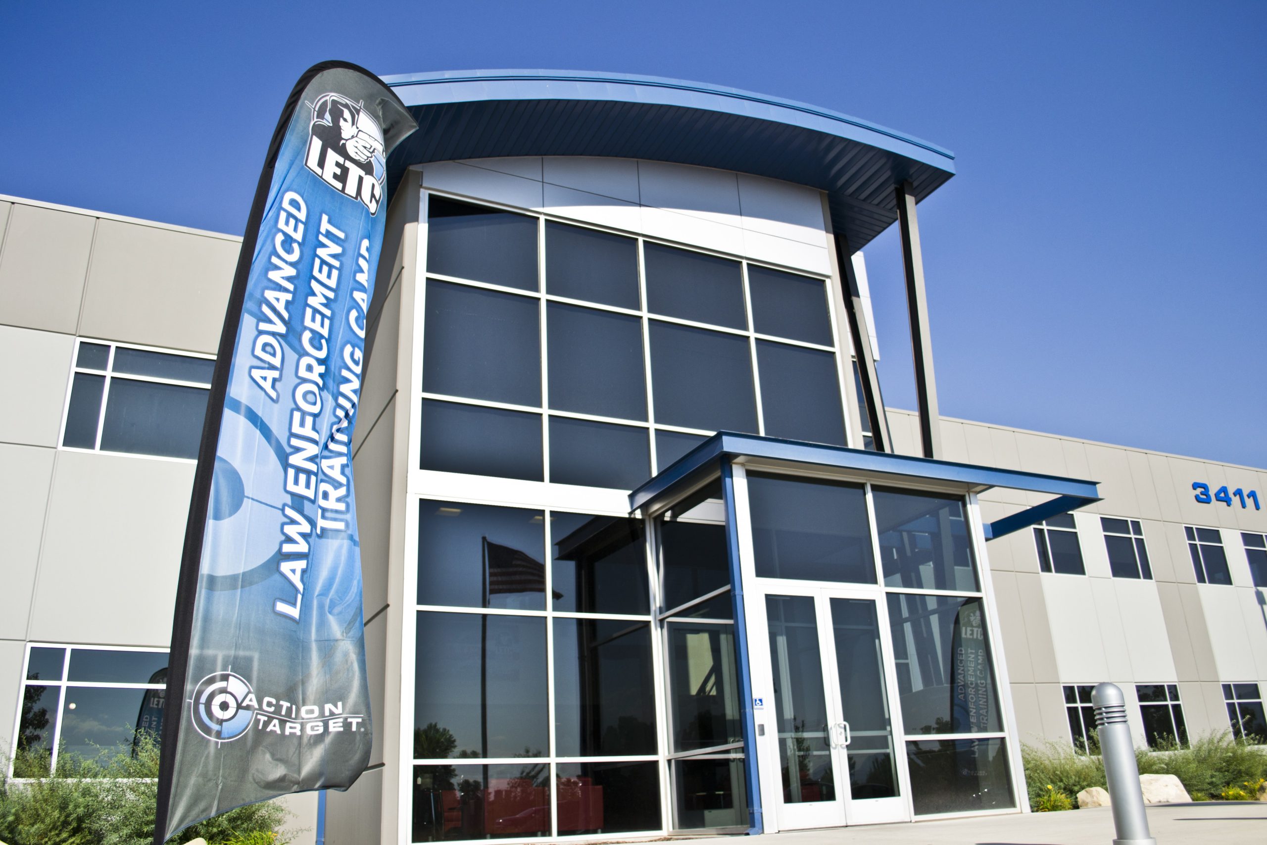 Exterior view of Action Target building with a banner reading 'Advanced Law Enforcement Training Camp' beside the entrance.