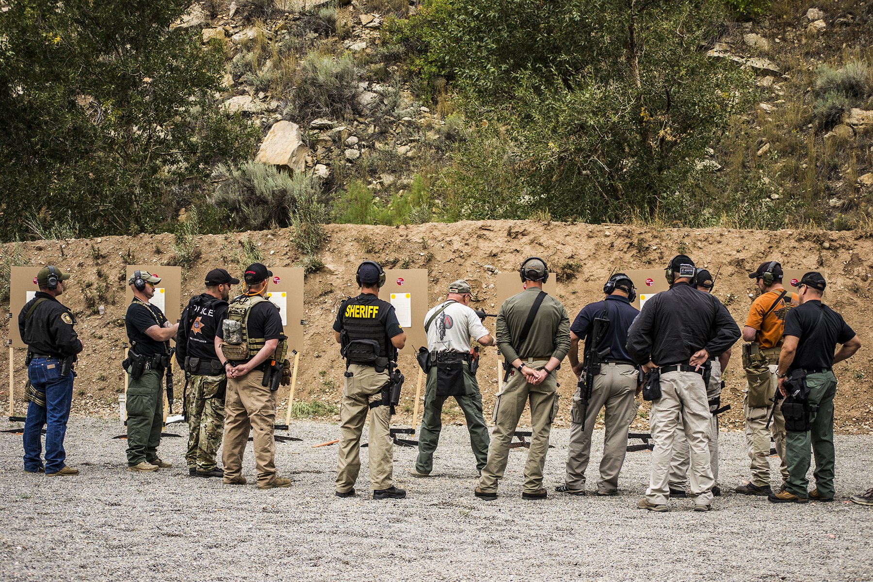 Group of law enforcement officers training at an outdoor shooting range while observing target results.