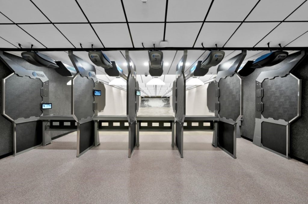 Shooting range with multiple lanes, dividers, and target tracks in a well-lit indoor facility.