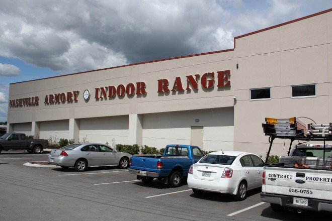 Building labeled "Nashville Armory Indoor Range" with parked vehicles in a lot under a cloudy sky.
