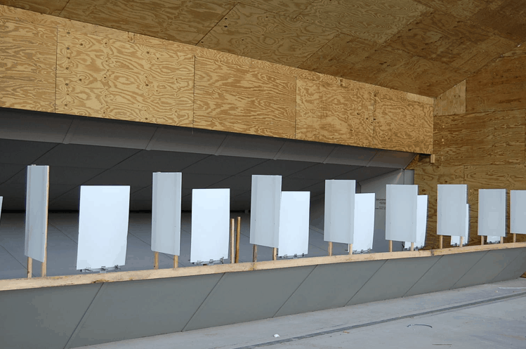 White wooden panels line a shooting range, set against a backdrop of plywood walls.