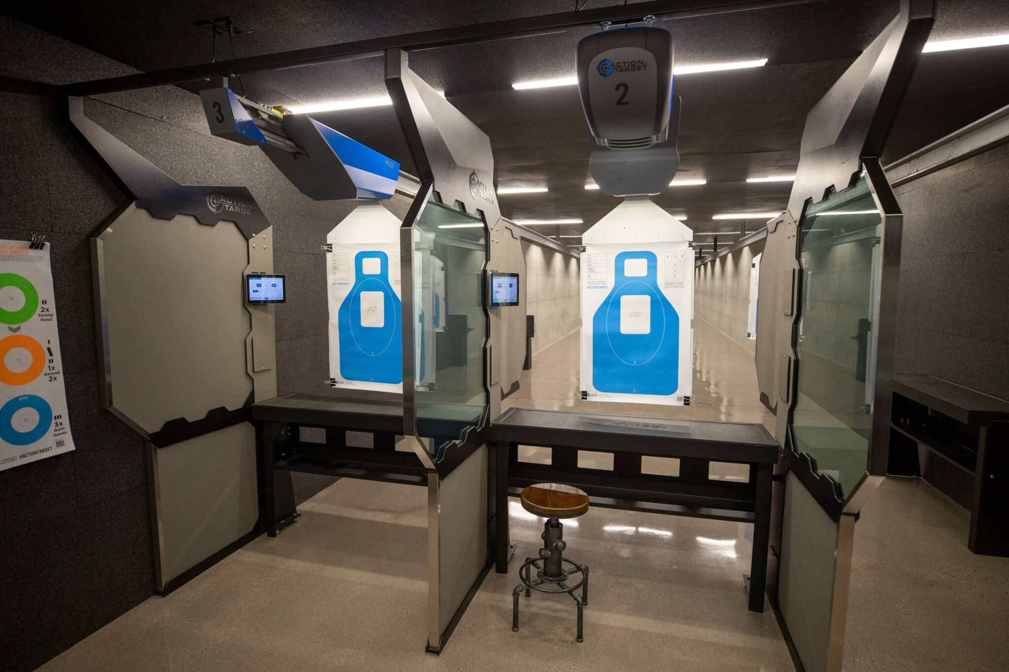 Modern indoor shooting range with Action Target stalls, digital controls, and blue silhouette targets.