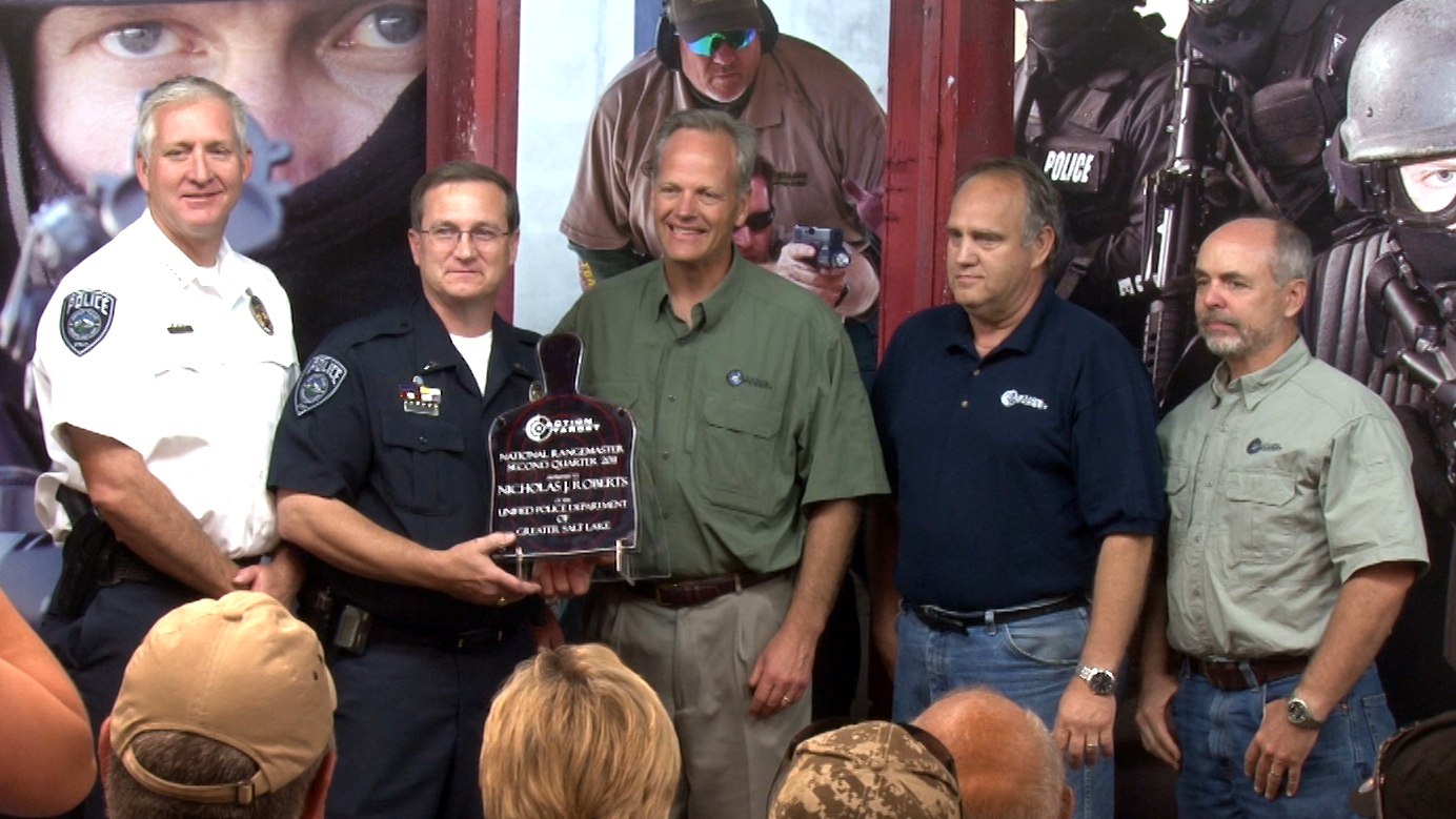 Group of men presenting a National Rangemaster award, with a police officer holding a trophy shaped like a shooting target.