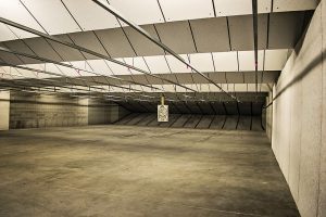 Target hanging in an indoor shooting range with concrete walls and ceiling panels.