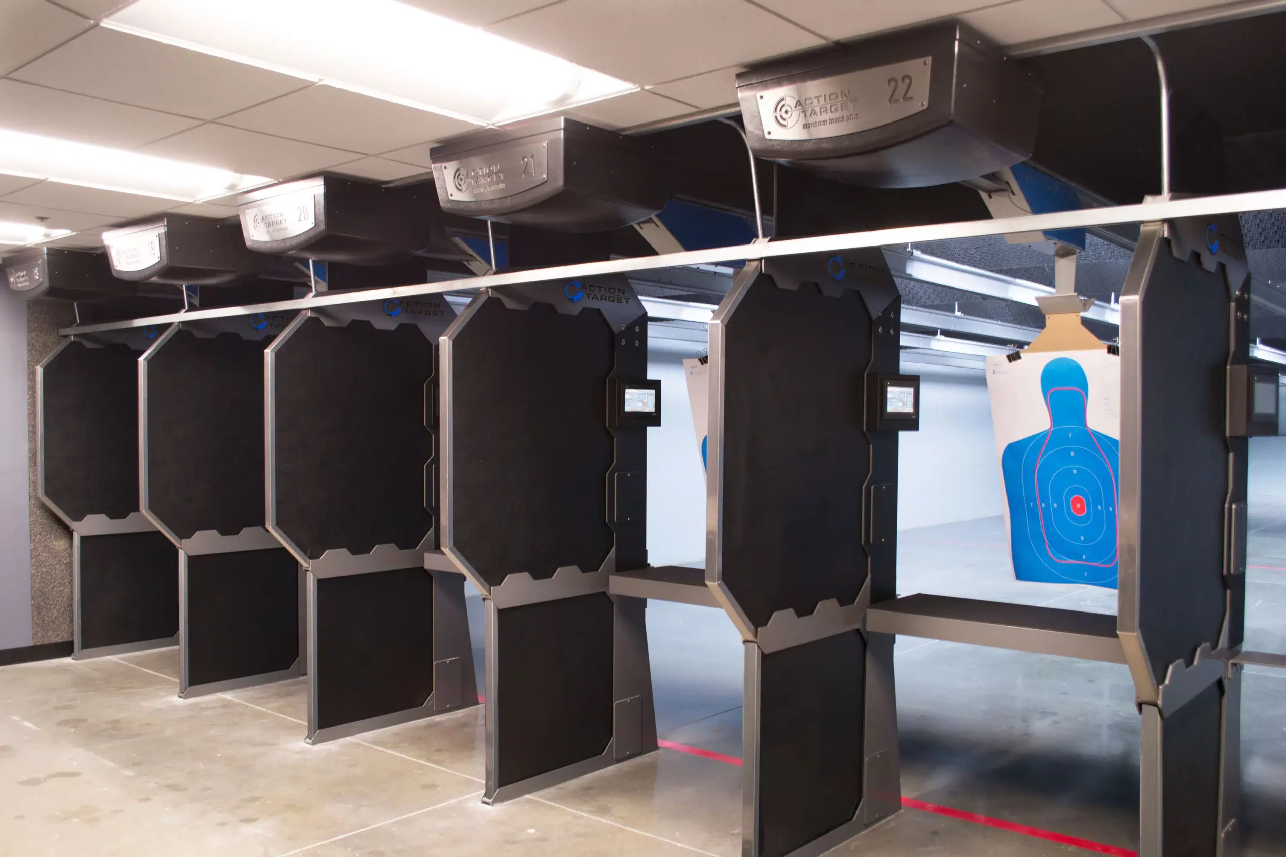 Shooting range stalls with dividers, target suspended; indoor, well-lit.