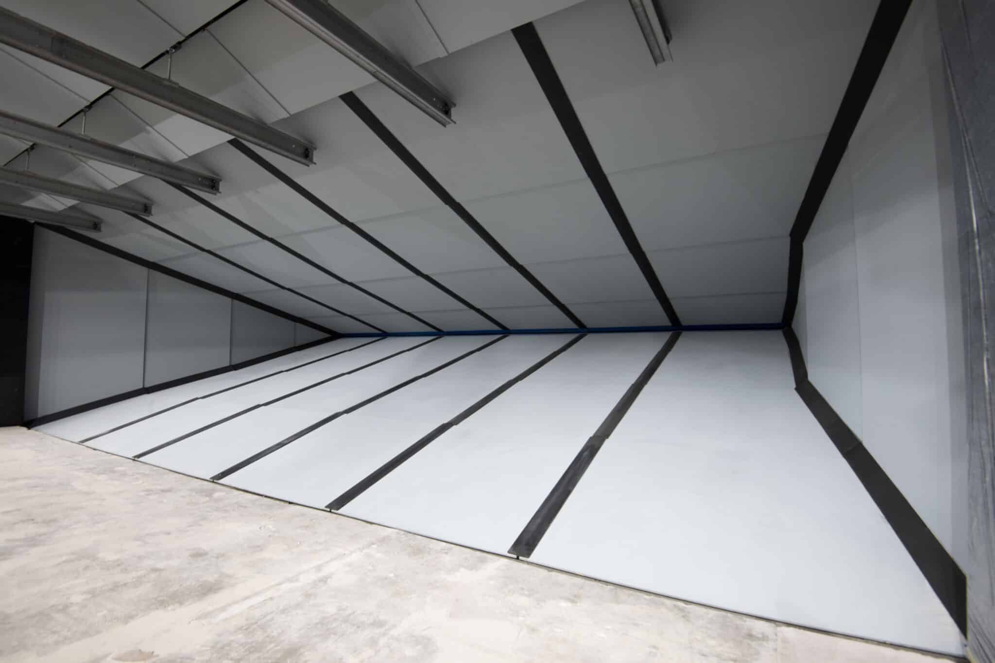 Sloped metal roof structure with support beams in unfinished indoor space.