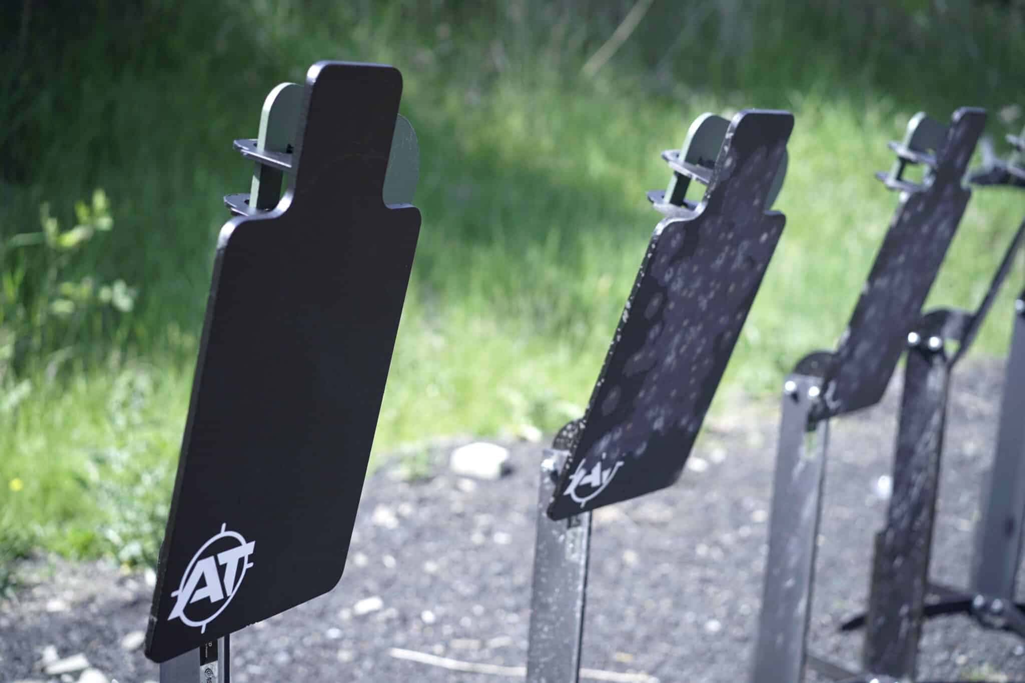 Row of black steel silhouette targets with Action Target logos set up at an outdoor shooting range.