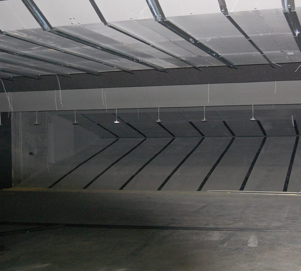 Indoor shooting range with angled steel bullet trap panels and suspended target system.