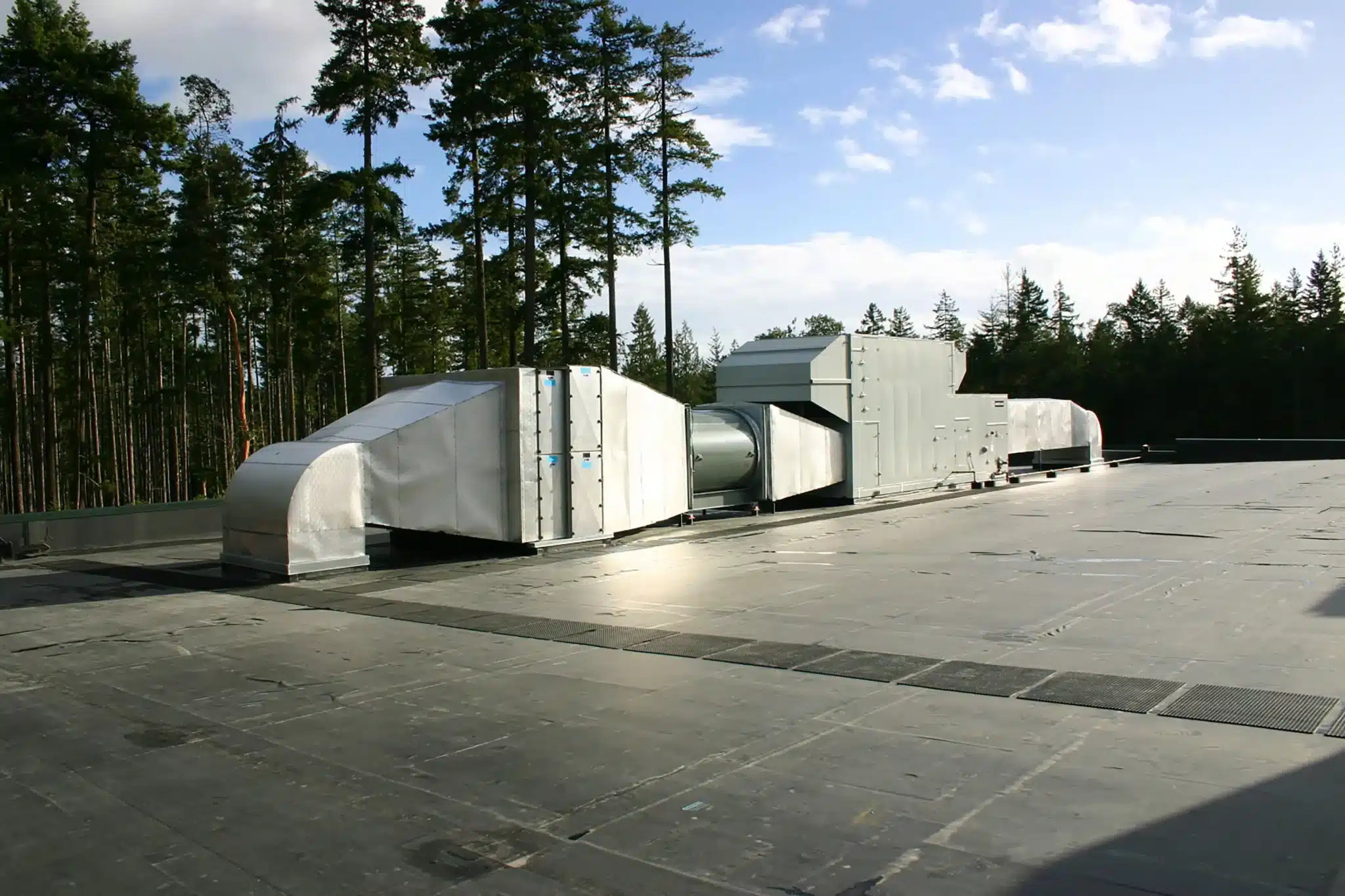 Large rooftop HVAC ventilation system surrounded by trees.