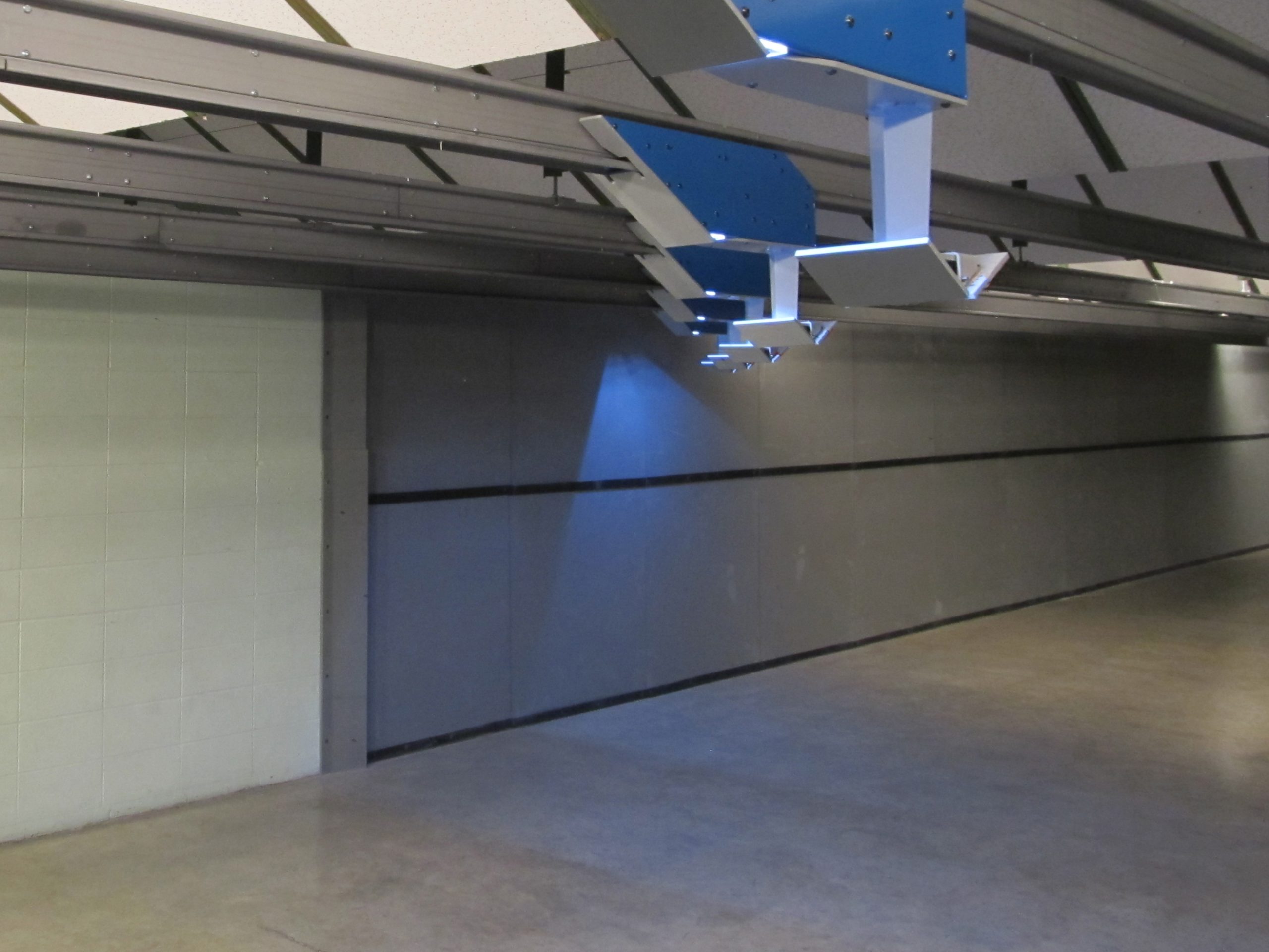 Indoor shooting range targets hang from ceiling tracks; concrete floor and gray walls.