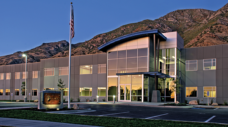 Action Target corporate headquarters building with glass facade, flagpole, and mountain backdrop.
