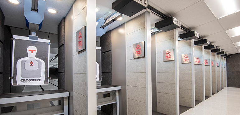 Target hangs in an indoor shooting range; lanes and target numbers visible. Text: “CROSSFIRE.”