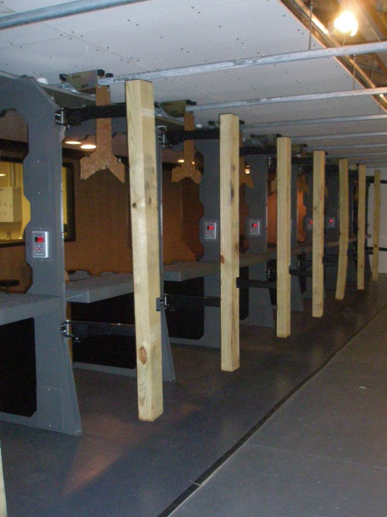 Wooden beam dividers stand in a row at an indoor shooting range.