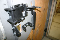 Close-up of a heavy-duty mechanical door locking and hinge system with metal brackets, bolts, and chain components.