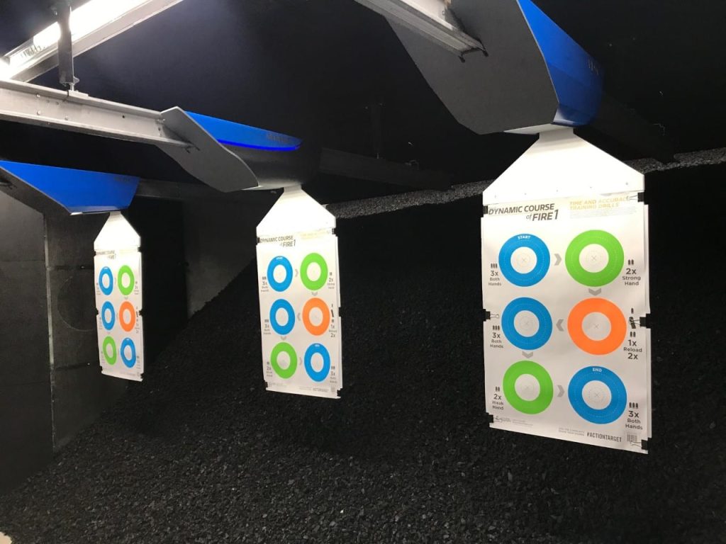 Targets hanging in indoor shooting range; blue and green colored circles on paper.