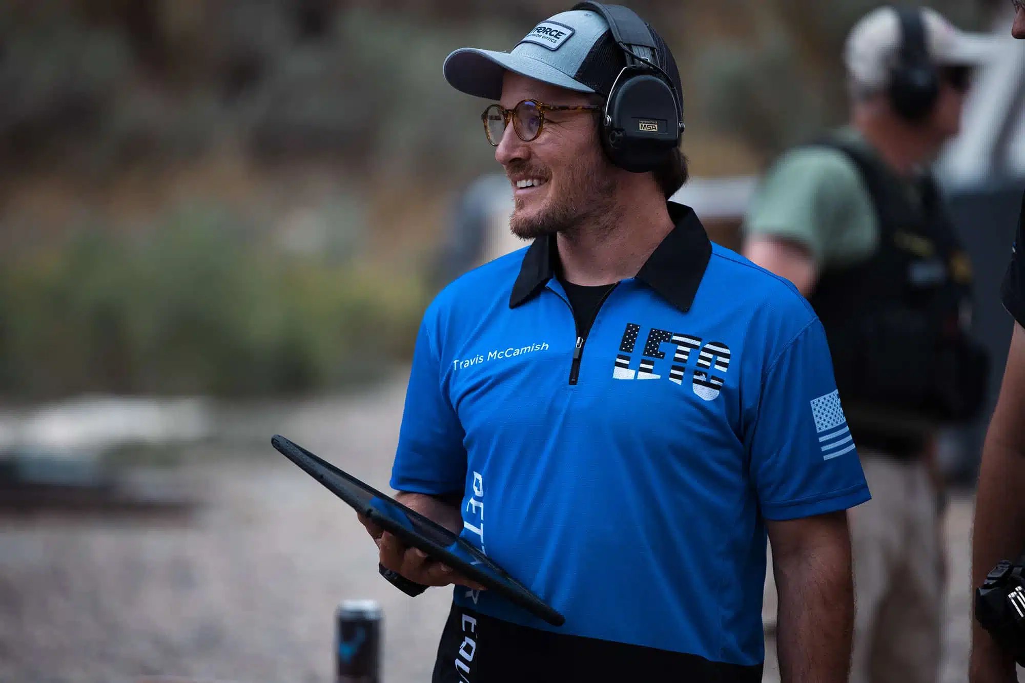 LETC instructor wearing blue Action Target shirt holding a tablet while outside