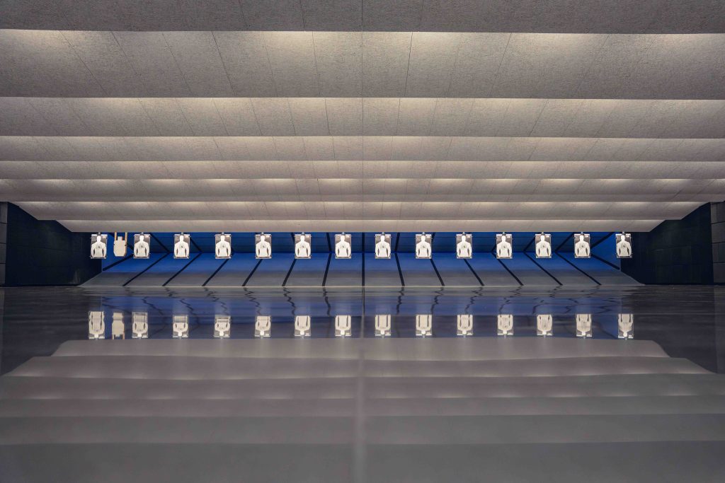 Indoor shooting range with multiple silhouette paper targets lined up across lanes