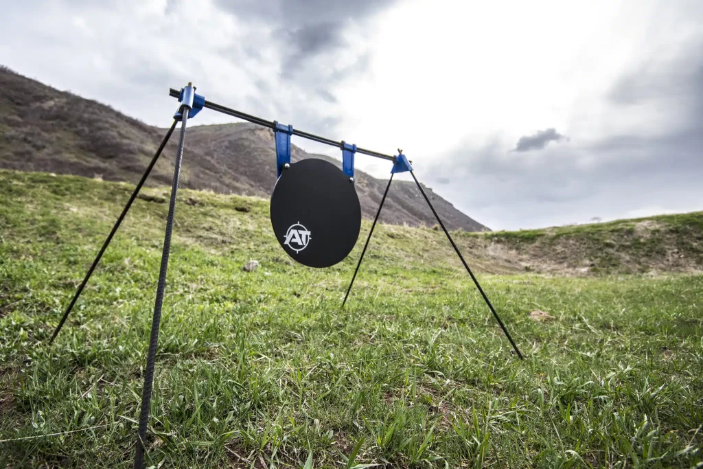 Steel gong shooting target mounted on a portable stand at an outdoor shooting range.