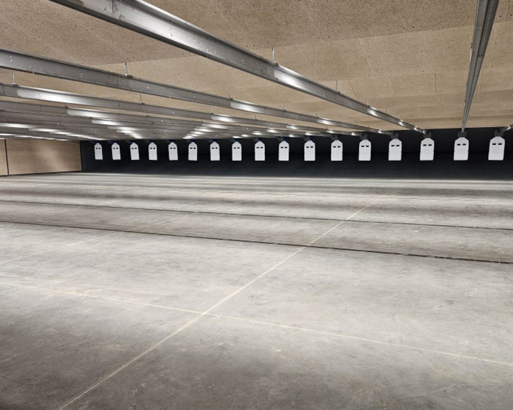 Targets hang in an indoor shooting range with a concrete floor and overhead lights.